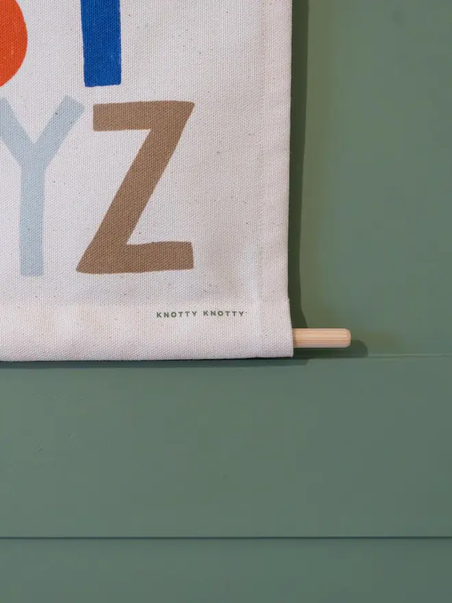 Rainbow Alphabet Fabric Banner, hanging on a green wall. 
