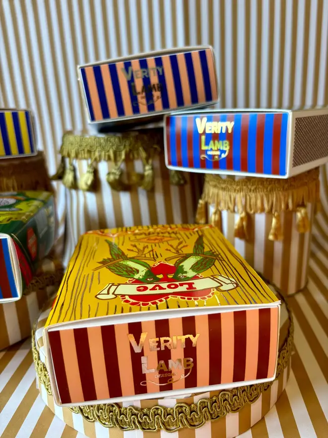 The Crown Jewels Matchbox, a red matchbox with a crown design sitting on a decorated surface accompanied by other accessories. 