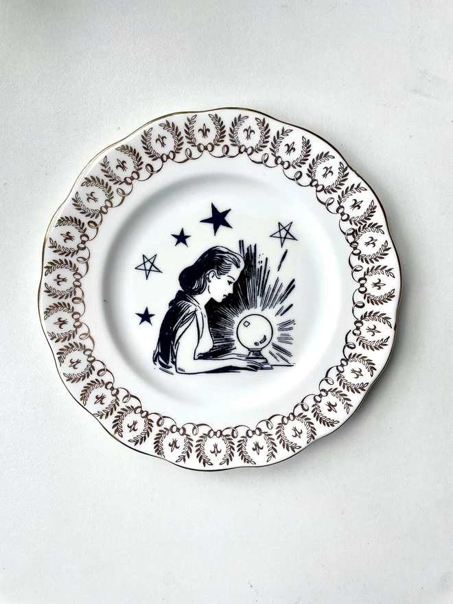 a vintage ornate plate with a pink floral border detail, in the centre i have printed a vintage black and white illustration of a pretty fortune teller reading a crystal ball