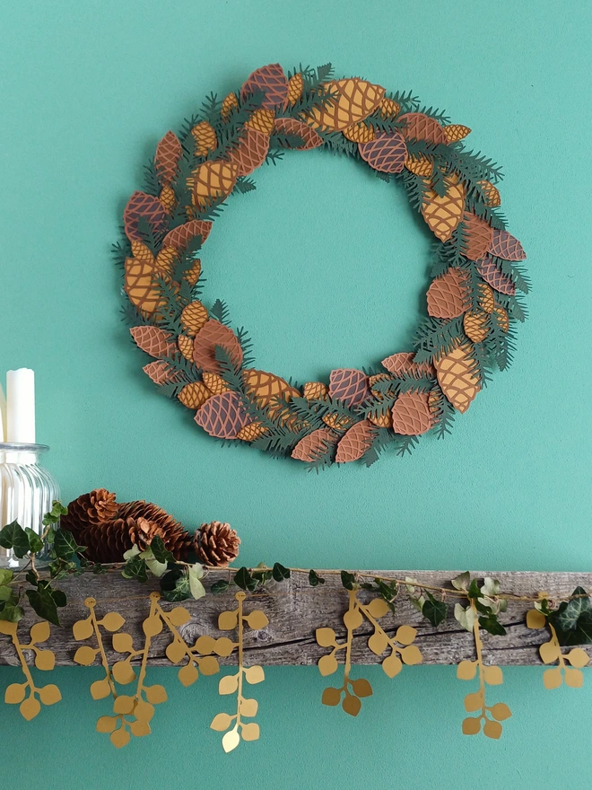 Christmas Pinecone Wreath hung on wall above mantelpiece decorated with gold berry garland