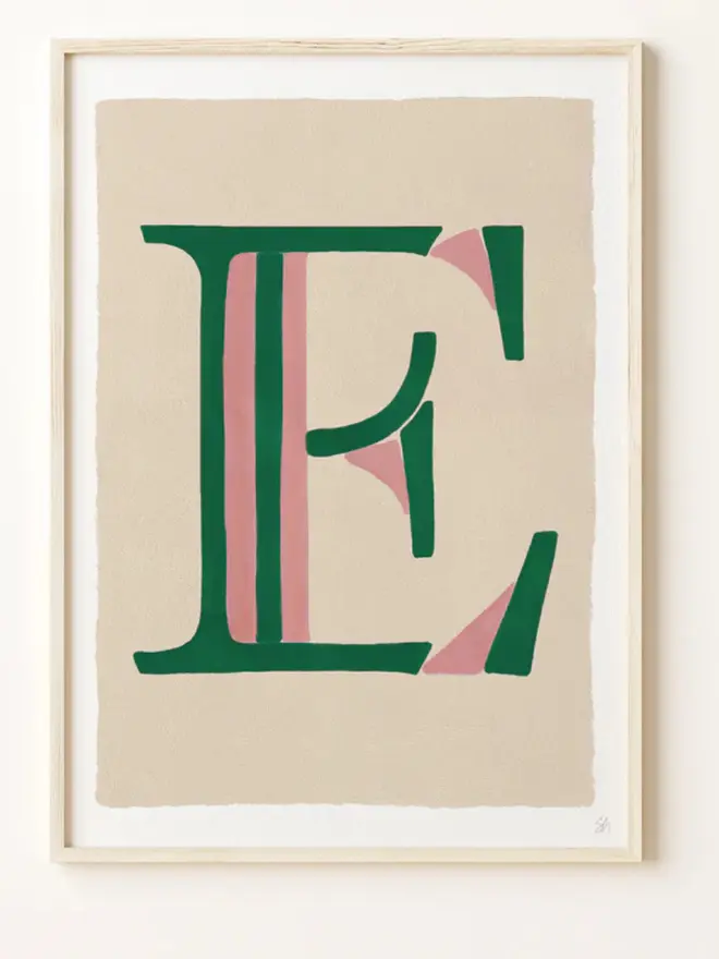 Framed wall art print featuring a large decorative letter “E” in humbug stripes centered on a white background. 