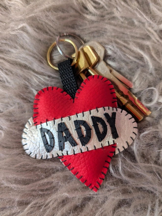 A red leatherette heart keyring, with black lettering spelling Daddy across a white scroll