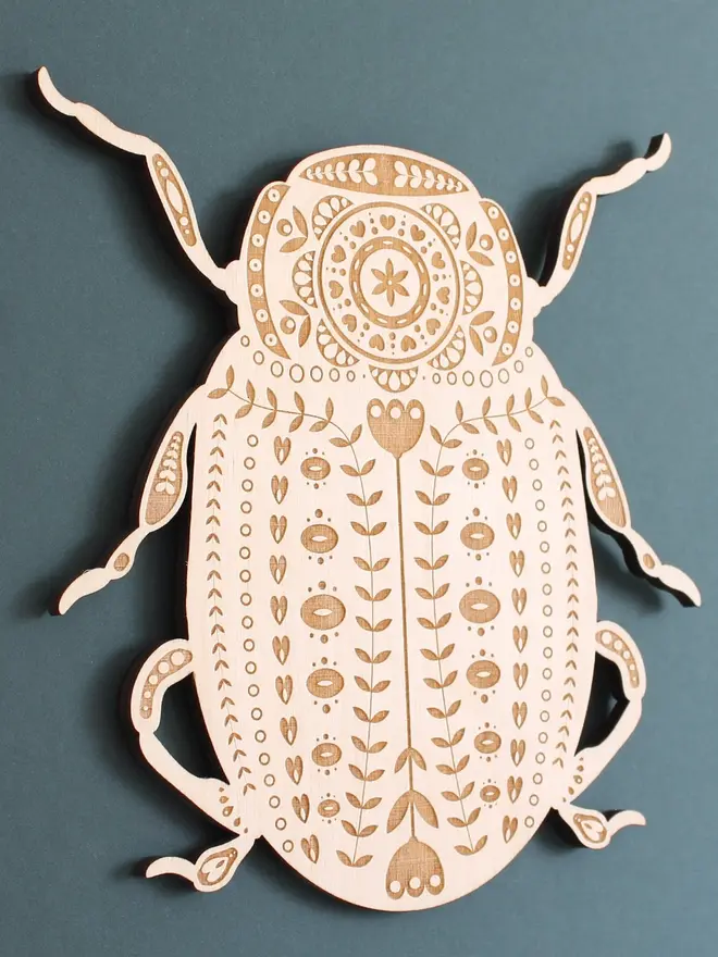 Folk Art Beetle Wall Hanging, wooden insect decoration hanging on a wall. 