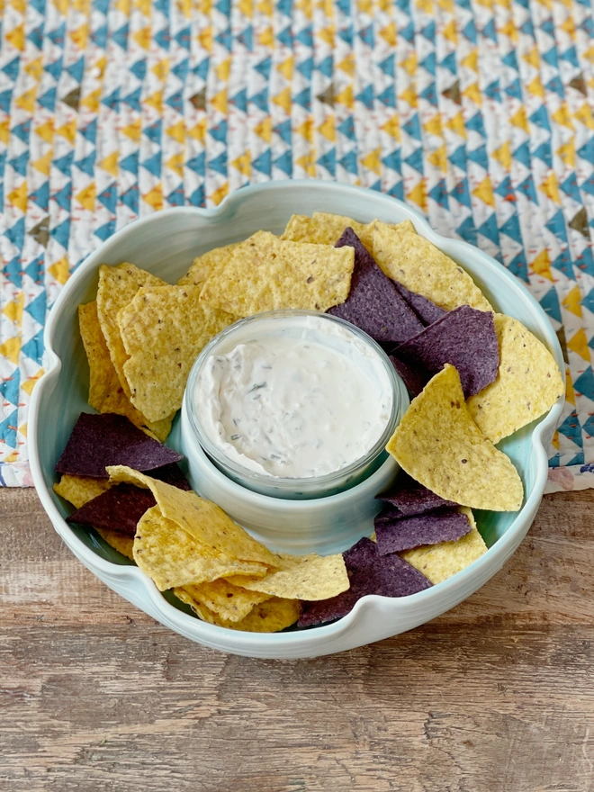 flower shaped chip and dip bowl on table with tortilla chips and dip