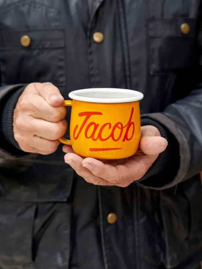 man holding yellow mug with 'jacob' script text