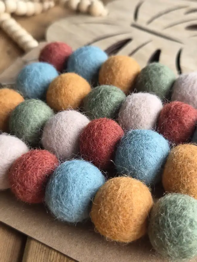 Felt ball bunting wrapped around card in muted tones.