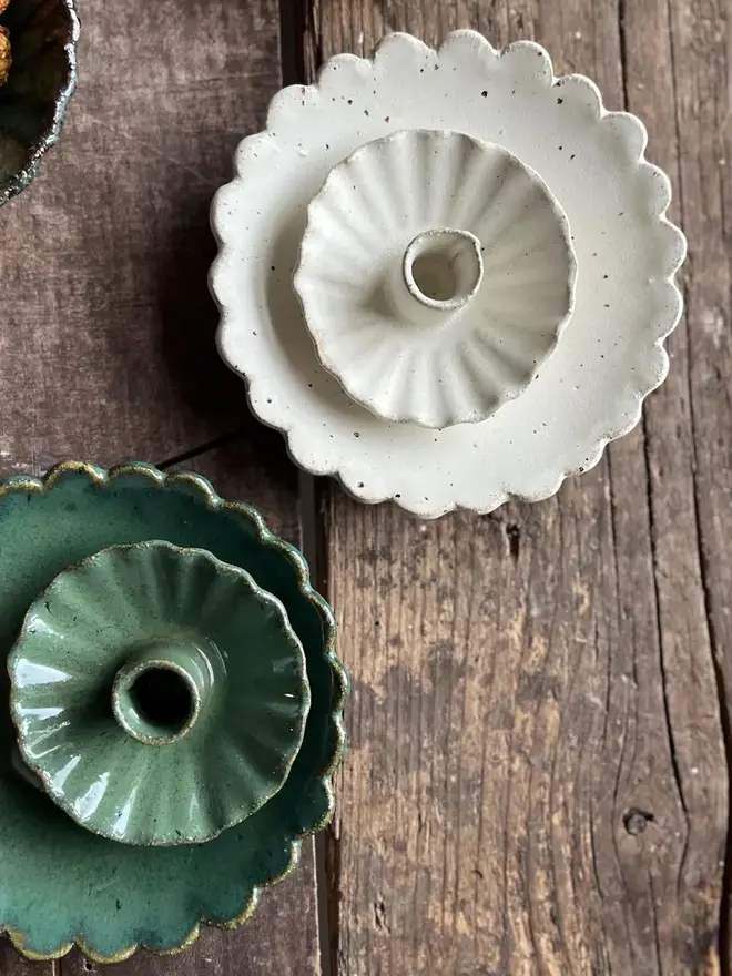 Handmade Green Ceramic Candlestick Holder, a pair of green candlestick holders sitting on a wooden surface. They are accompanied by other ceramic candlestick holders. 