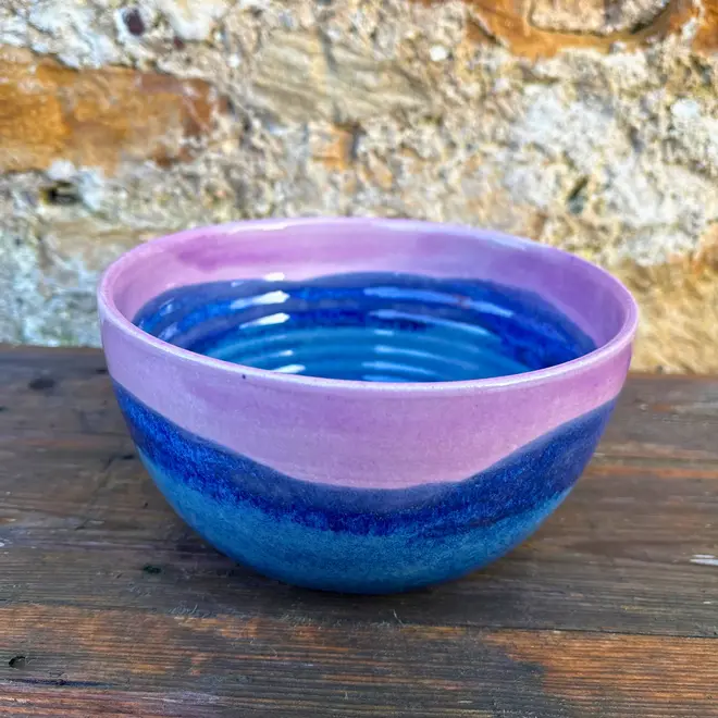 Landscape Ramen Bowl, a of colourful ramen bowl placed on a wooden surface in front of a brick backdrop. 