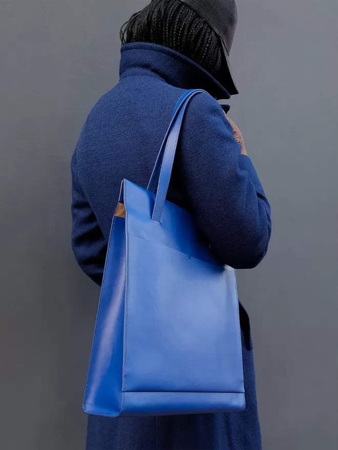 Cobalt Blue Tote Bag worn on a Royal Blue Jacket. The model is facing away from the camera with a modern camouflage print cap.