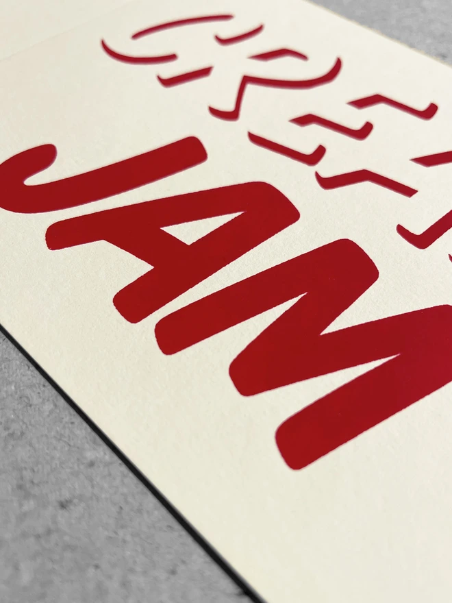 Close up of red ink printed on cream card, with the word Jam is in sharp focus.