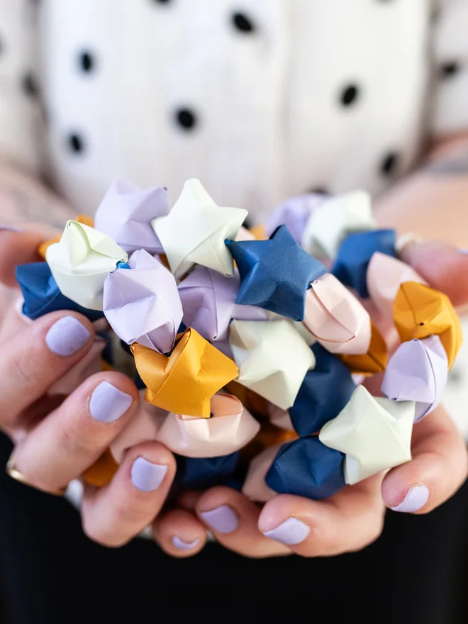 Woman holding a star garland altogether in her hands.