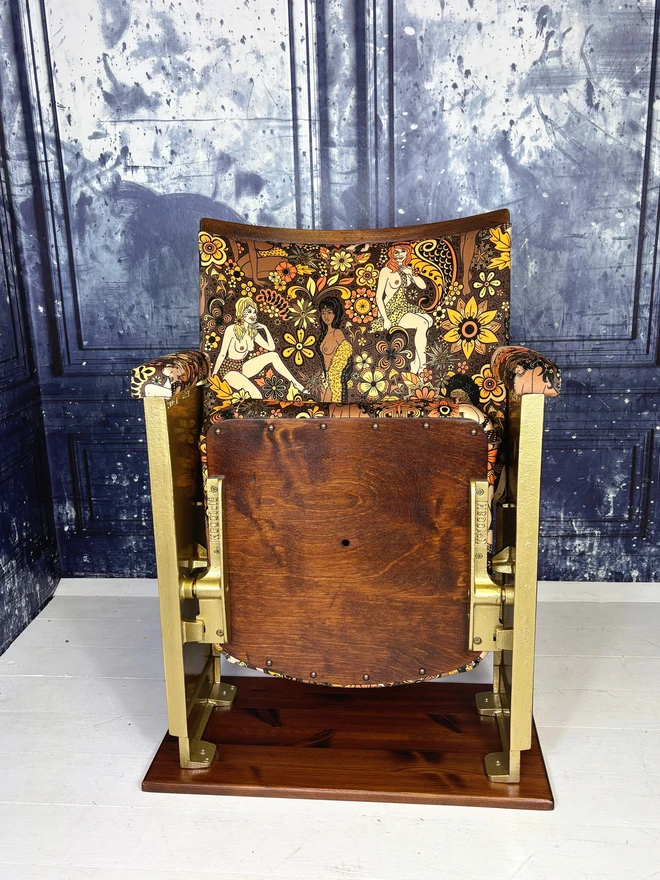 Refurbished vintage cinema seat upholstered in Summer of Love velvet.  The flip down part of the cinema seat is closed showing off the wood base.  The cinema seat has gold legs.