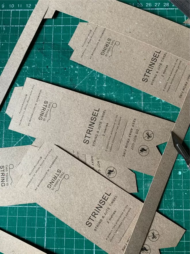 Handmade Strinsel – string tinsel – labels on kraft card being cut out on a green cutting mat