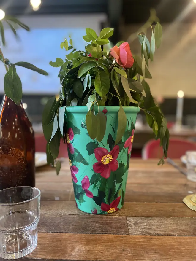 unique hand-painted terracotta interior pot featuring deep pink anemone on a turquoise background