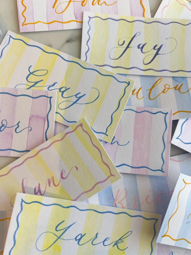 Personalised calligraphy event place cards, striped coloured place cards spread together