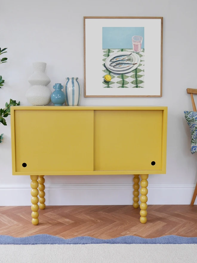 Yellow cabinet with sliding doors and bobbin-style legs in a cozy cottage