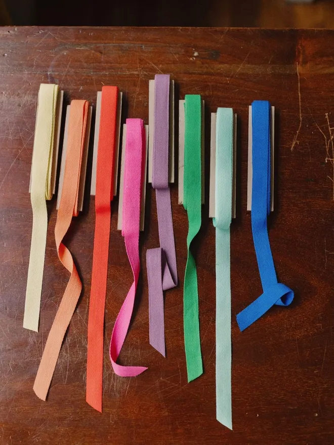 Cotton herringbone ribbon in lots of colours on a wooden surface