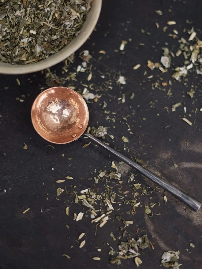 Copper And Stainless Steel Scoop, a metal scoop sitting on a bowl of herbs. 