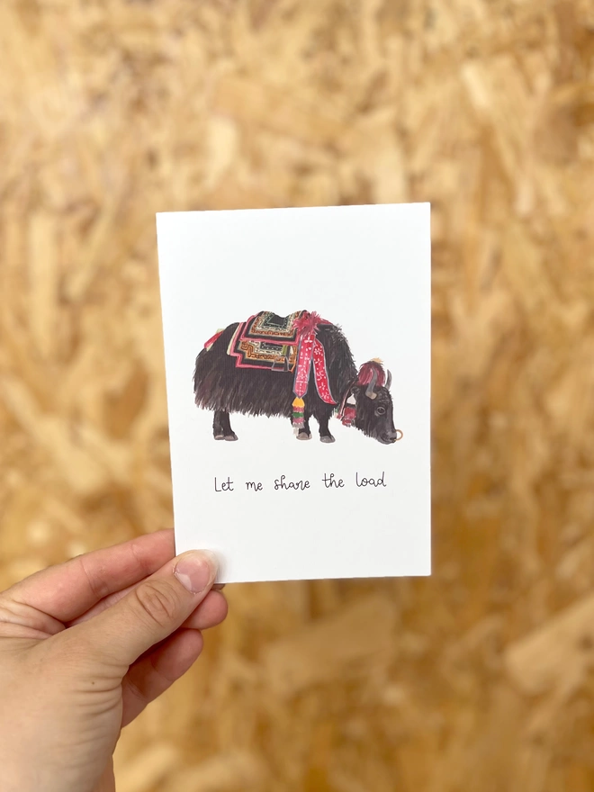 a greetings card featuring a domestic yak carrying a bag and the phrase “Let me share the load”