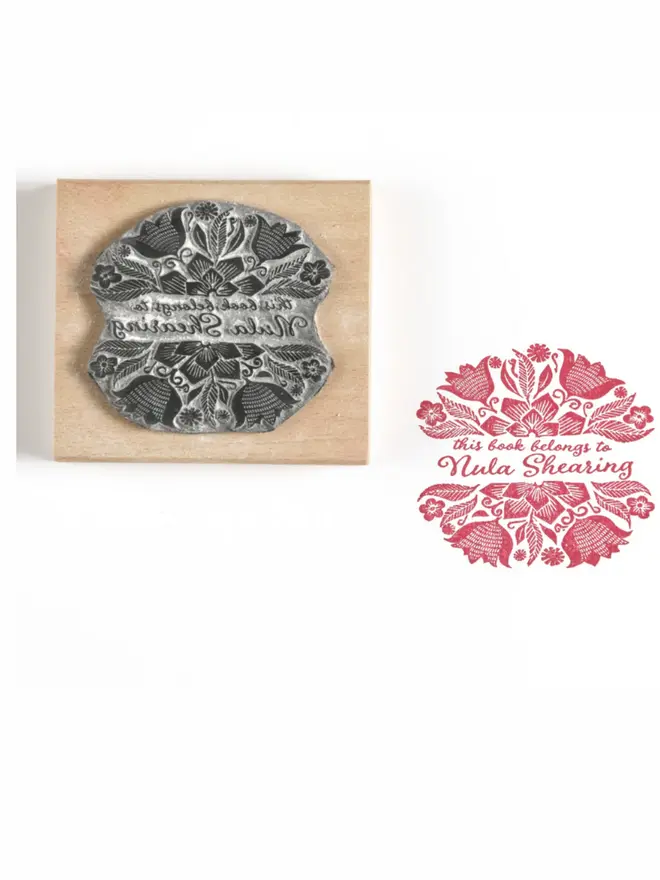 Wooden rubber stamp with an ornate Mexican floral design, shown alongside a red ink stamped impression reading ‘This book belongs to Nula Shearing’.