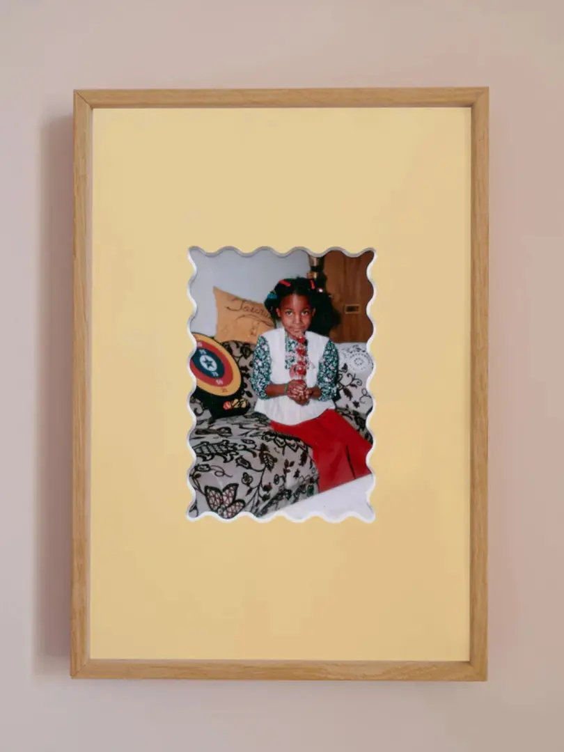 Ric rac photo mount frame with a yellow mount featuring a decorative ric rac boarder around a centered Instax photo, displayed on a neutral beige wall.