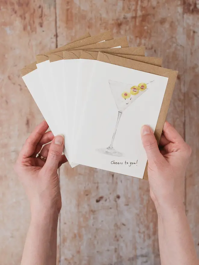 Hands holding a bundle of 6 drink themed cards featuring Martini Card 