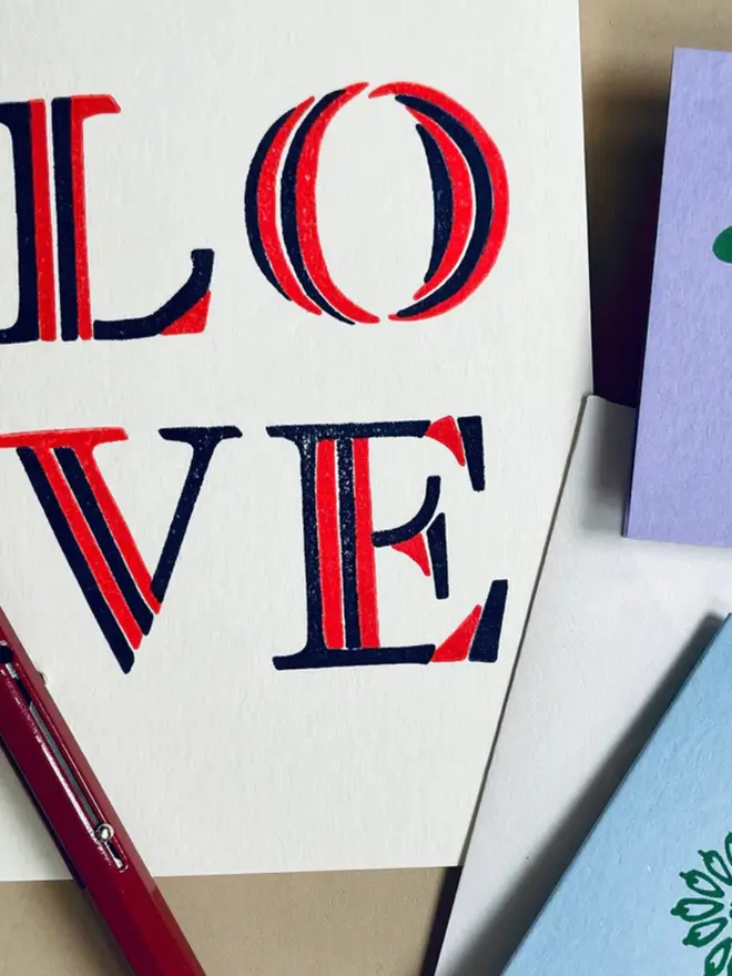 'Love' stripe hand printed card displayed on a table with other cards. 