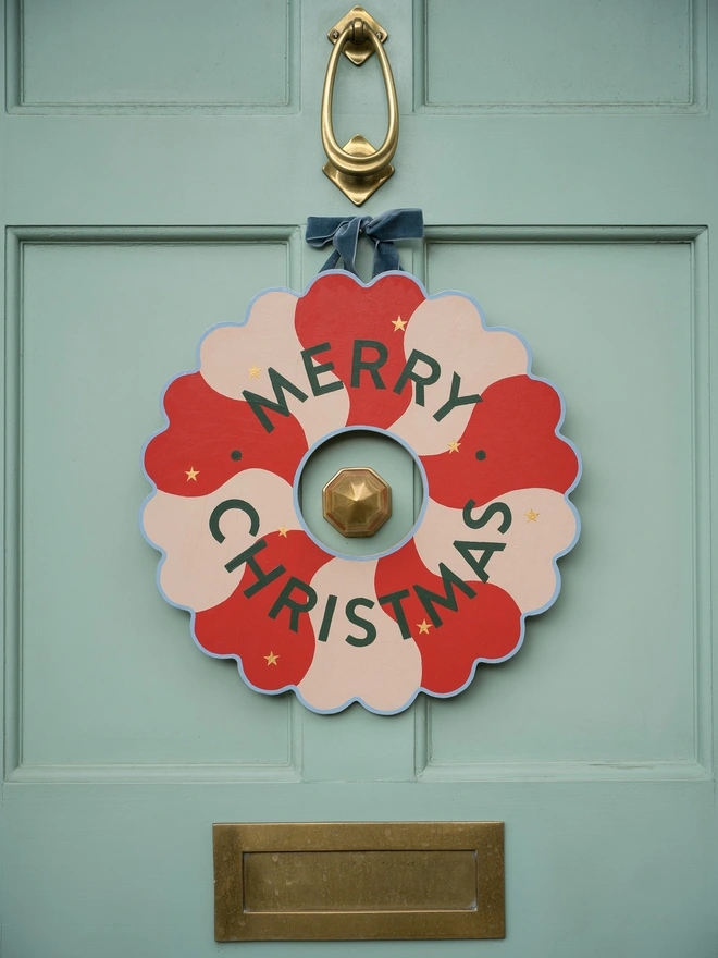 Red and pale pink Hand painted Christmas Wreath with gold leaf stars on a pale green front door