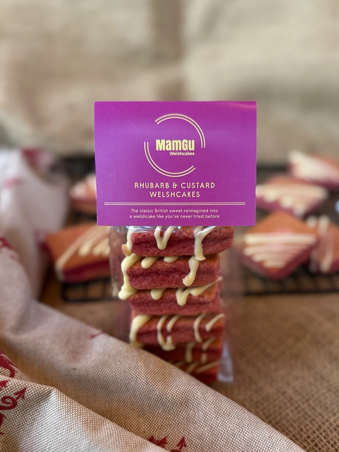 pack of Rhubarb and Custard welsh cakes with a pink label on a rustic kitchen worktop