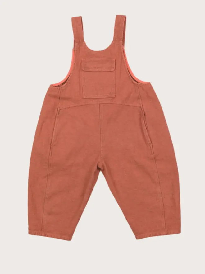 AW25 Kai oversized denim dungarees in coral overdye with curved seams and adjustable straps