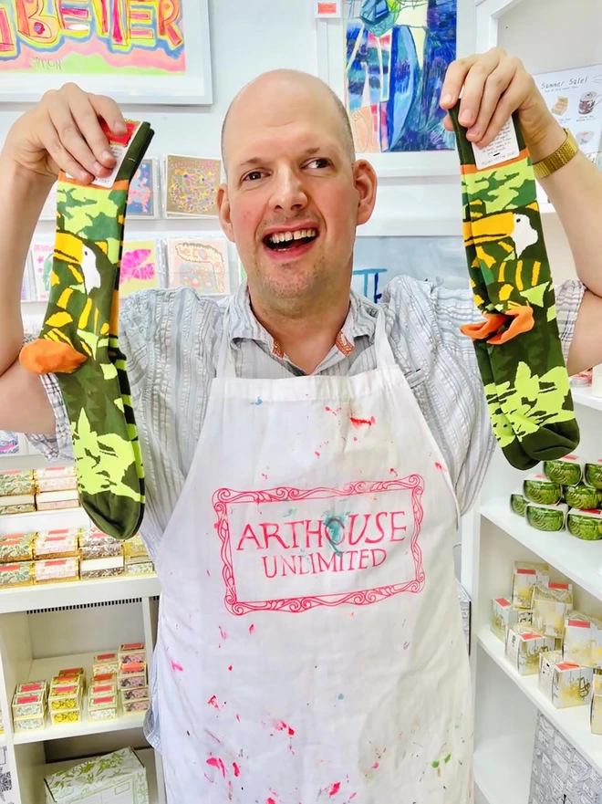Happy artist holding amazon 100% organic charity cotton socks in green & yellow