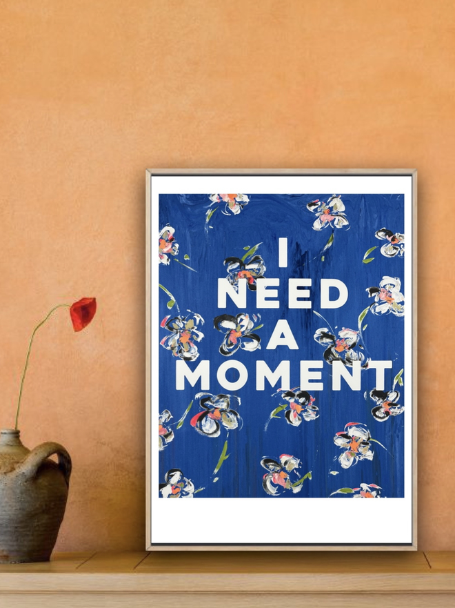 I NEED A MOMENT fine art print by M.E. Ster-Molnar.  Based on an original monoprint by M.E. Ster-Molnar.  Shown here against a sunset colored orange stucco wall and next to a single red poppy and handmade pot.  
