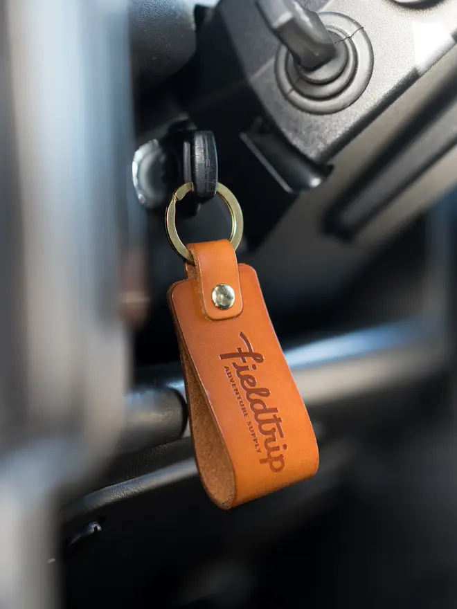 'fieldtrip' handmade leather keyring. a leather keyring embossed with the word 'fieldtrip' hanging from a car ignition.