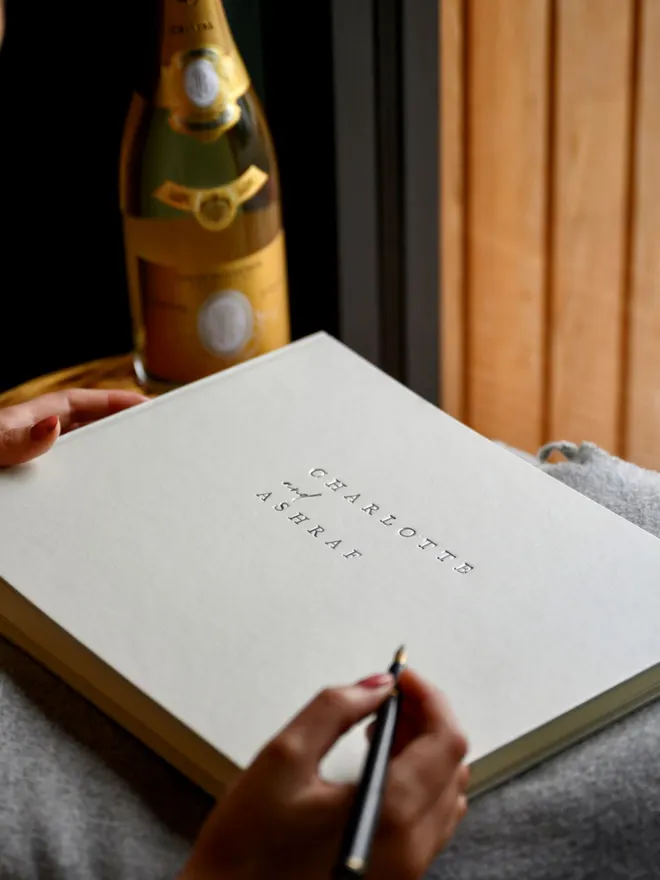 Ivory-coloured 'Jewel' Covered Landscape Wedding Guest Book, on a table.