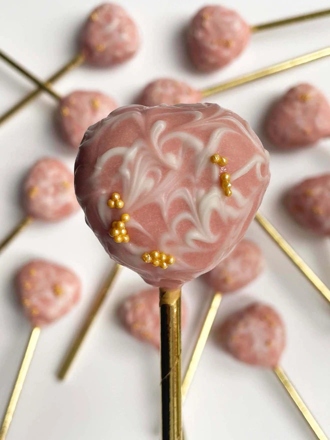 Valentines Marble Heart Cake Pops (Pack Of 6, 12, 18, 24), single cake pop held inform of a background on marble heart cake pops on a white background.