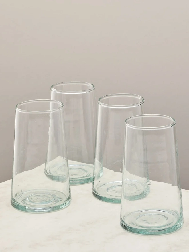 Highball Glasses (Set Of 1 Or 4), a group of highball glasses sitting on a plain counter top against a white backdrop. 