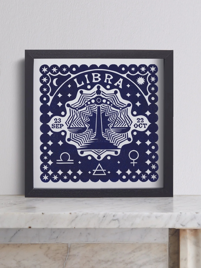 libra zodiac linocut. a linocut set of scales and zodiac symbols printed on a blue background.