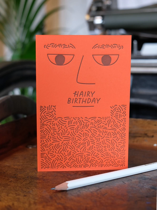 Tangerine letterpress printed bearded man card on shelf.