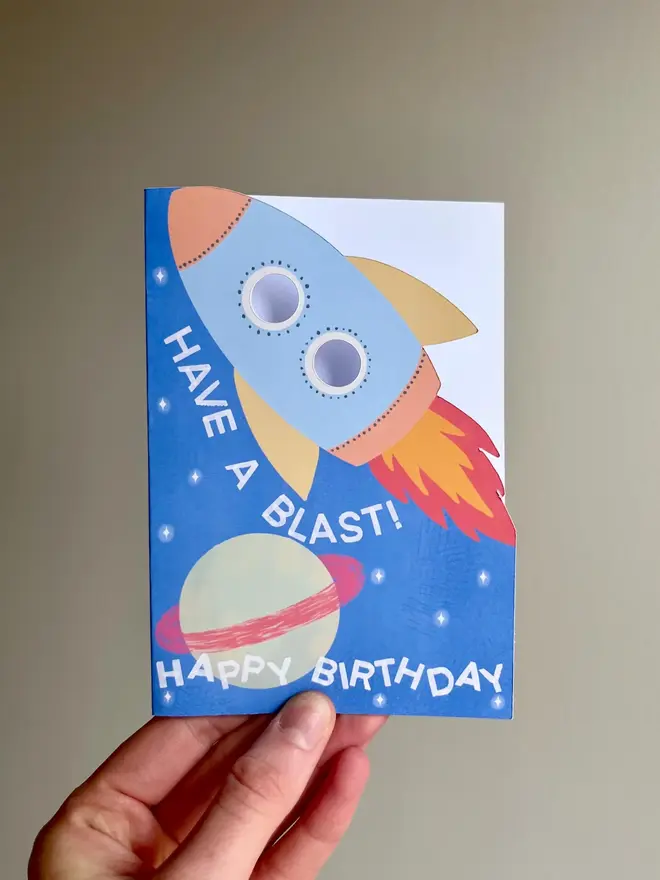 have a blast rocket birthday card. blue card with illustrated rocket and planets.