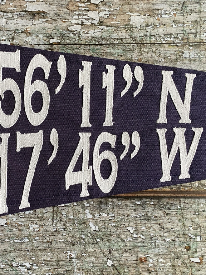 Detail of a coordinates pennant flag showing ivory canvas numbers