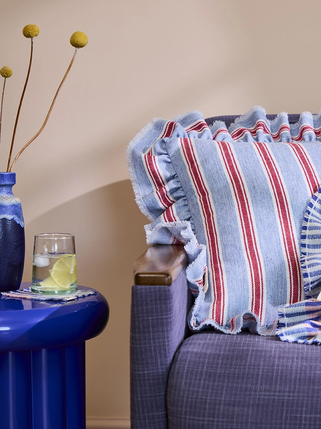 Blue Raspberry Cushion. Cushion on sofa next to side table.
