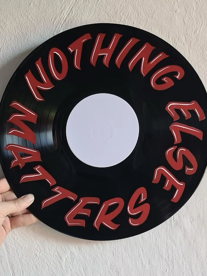 'Nothing Else Matters' Vinyl Artwork, a person holding a colourful vinyl artwork above a stone surface. 