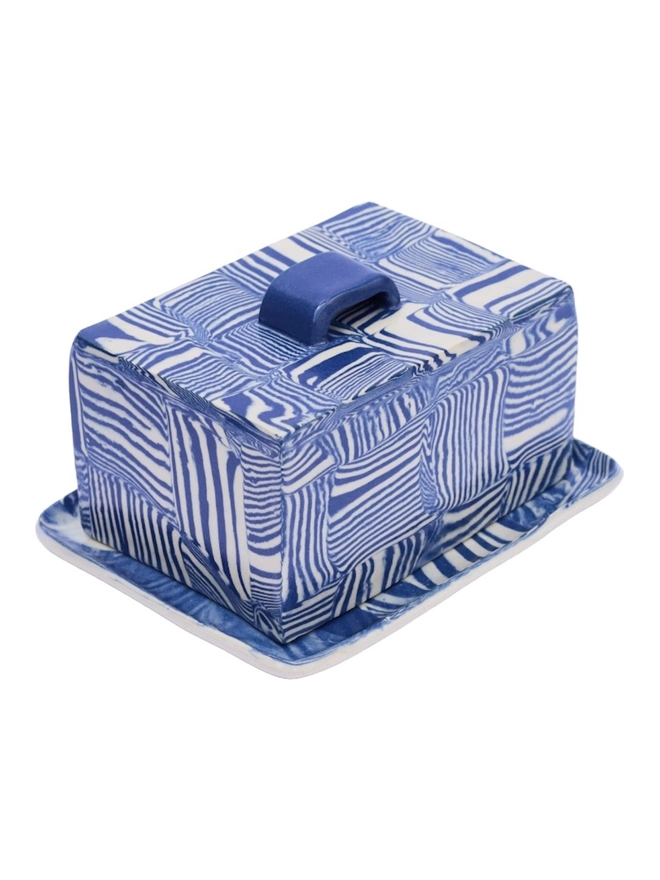 Striped Butter Dish, a colourful striped butter dish sitting on a white surface against a plain backdrop. 