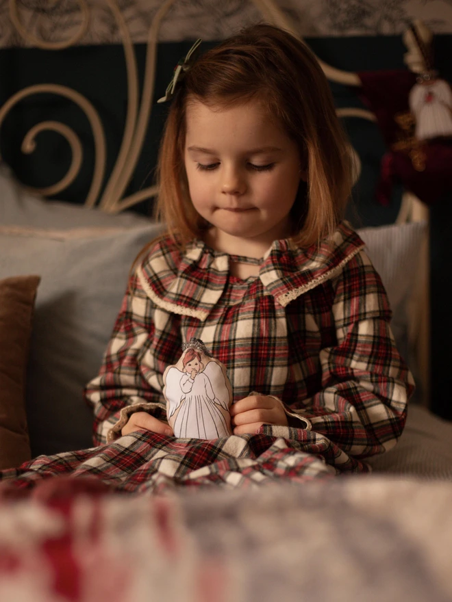 a sweet little girl holding a plush Christmas tree angel decoration