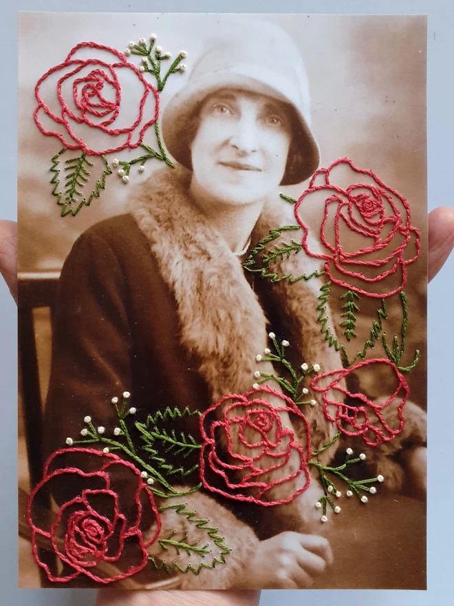 Photo of a woman with hand embroidered rose surrounding her, held against a grey background
