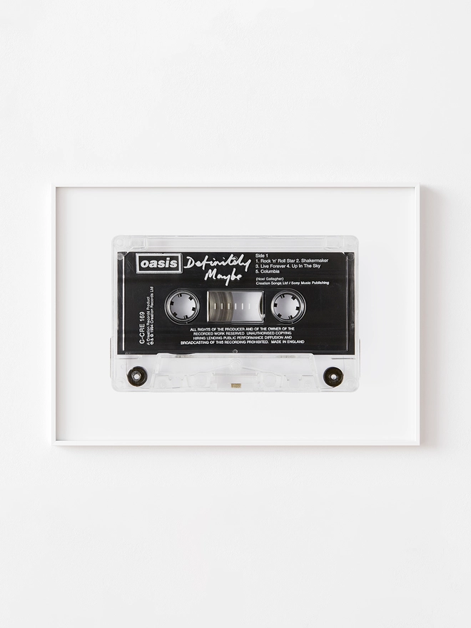 oasis definitely maybe cassette tape print. framed print hung up on white wall.