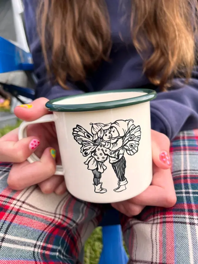 child holding the mug showing an etching of two butterfly pixies with green rim