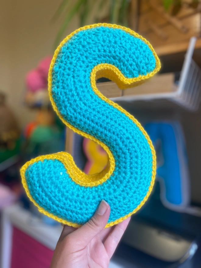 Crochet cushion shaped like the letter S in Teal and Sunshine Yellow