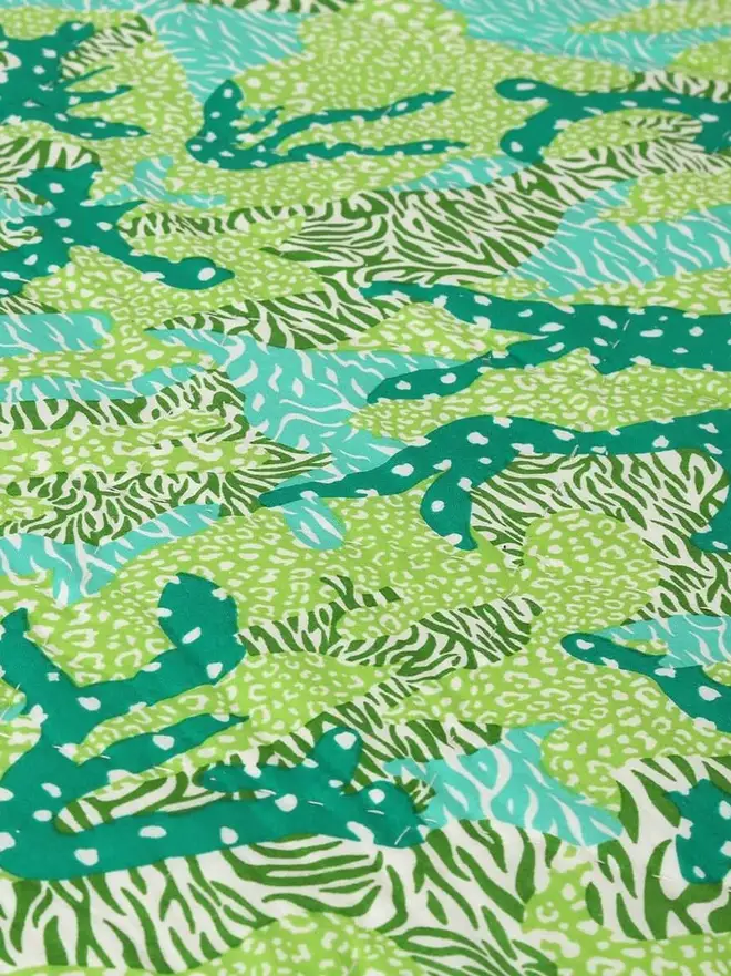 Big Cat Camo Quilt, a pink and green quilt on a bed in a bedroom. 