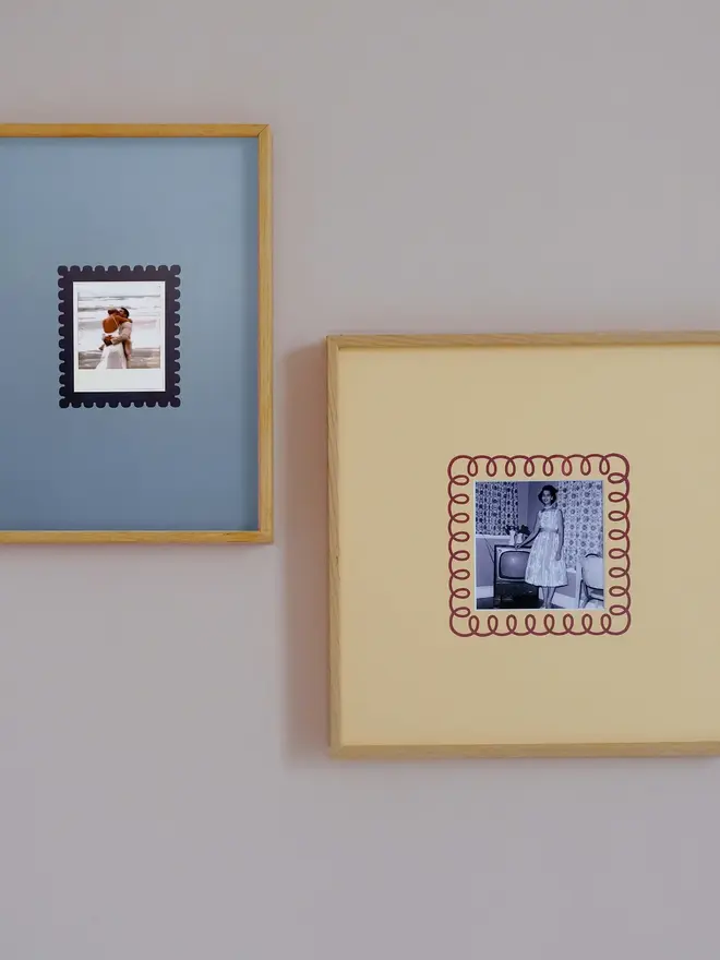 The Scallop Instax Square Mount frame with a yellow and blue mount featuring a decorative scallop border around a centered Instax Square photo, displayed on a neutral beige wall.